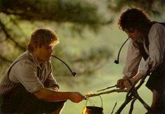 two men are cooking over an open fire