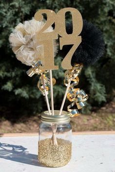 a mason jar filled with gold glitter and some decorations on top of a white table