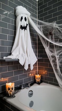 a bathroom decorated for halloween with candles and ghost towels hanging from the wall above the bathtub