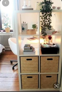 a white shelf with drawers and plants on top