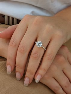 a woman's hand with a diamond ring on her left hand, and a man's arm behind her