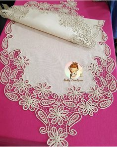 a pink table with white lace on it and a roll of paper next to it