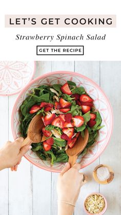 a person holding a wooden spoon over a bowl filled with spinach and strawberries