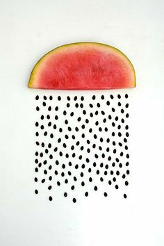 a slice of watermelon hanging from the side of a white wall with black dots