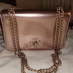 Tory Burch Metallic Patent Leather Mercer Sholder / Crossbody Pre-Loved Condition Serial # 10005634 03-16 * 9" Wide 3" Deep Almost 6" Height * Lined Inside With Zipper Pocket, 3 Interior Card Slots. * Exterior Slip Pocket * Classic Tory Turn Lock Closer * The Chain Is Adjustable And Can Be Worn At Two Different Lengths. 23" Long For A Crossbody Look Or 12.5" Doubled For A Classic Sholder Look. * The Dust Bag Is In Like New Condition. * Has The Logo Across To The Top. * Black Pull Rope Closer With Gold Hardware ( Plastic Still On Hardware) 21" 1/2 Wide 21" 1/2 Deep * No Call Outs On The Dust Bag. * No Oder In Or On The Purse Or Dust Bag Ebb, * The Leather On The Outside Is Rosego Gold Rectangular Flap Bag With Branded Hardware, Gold Party Bag With Branded Hardware, Rectangular Party Shoulder Bag With Branded Hardware, Tory Burch Bag, 16 9, Gold Hardware, Inside Pocket, Card Slots, Patent Leather