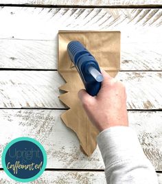 a person is using a pen to cut out a paper christmas tree ornament