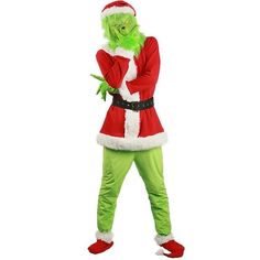 a man in a green and red costume standing with his hands on his hips while wearing a santa claus hat