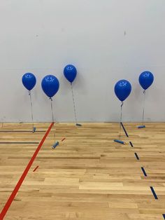 blue balloons are tied to the wall in an empty room with red tape on the floor