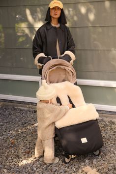 a woman standing next to a baby in a stroller