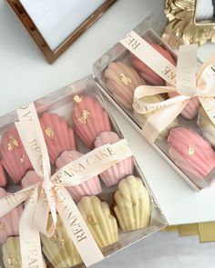 two boxes filled with pink and white cupcakes on top of a table next to a mirror