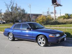 a blue car is parked on the side of the road in front of a basketball hoop