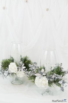 two clear vases with white flowers and greenery