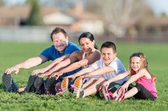 three adults and two children stretching on the grass