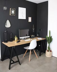 a desk with a computer on top of it next to a potted cacti