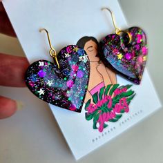 two heart shaped earrings with designs on them