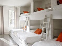 bunk beds in a room with white walls and orange pillows on the bottom bunks