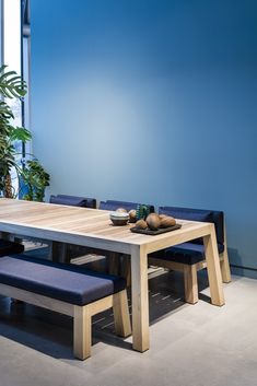 a wooden table with two benches next to it and a potted plant in the background