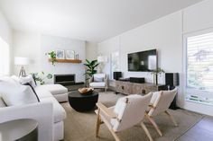 a living room filled with white furniture and a flat screen tv mounted on the wall