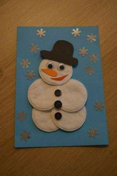 a snowman made out of felt sitting on top of a wooden table with snow flakes