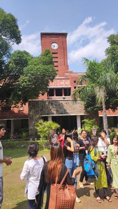 a group of people standing in front of a building with a clock on the tower