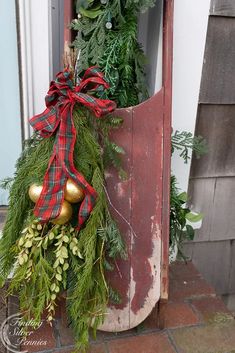 an old door is decorated with christmas greenery and bells for the holiday wreath display