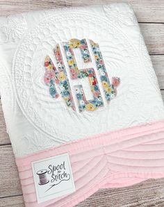 the monogrammed applique on this quilt is made from white and pink fabric