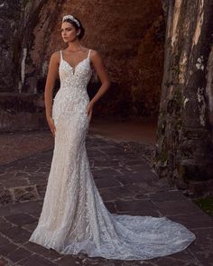 a woman in a white wedding dress standing on a stone walkway with her hands on her hips