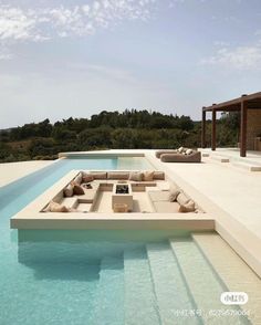 an outdoor pool with couches and tables next to it on the side of a house