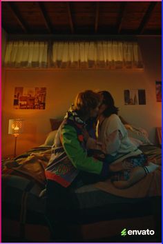 two people sitting on a bed kissing each other