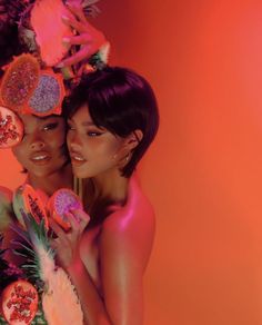 two beautiful women standing next to each other with fruit on their heads and holding lollipops