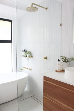 a white bath tub sitting next to a bathroom sink under a large mirror on the wall