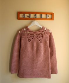 a pink sweater hanging on a coat rack