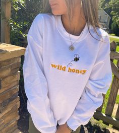 Enjoy a little wild honey with this adorable Bee Crewneck Sweatshirt. This sweatshirt features long sleeves, a crew neckline, and beautiful front embroidery. The Unisex Sizing makes the sweatshirt run slightly larger than your average sweatshirt for women. Most men find their normal size to be more snug. If you want a slightly looser fit, size up one size. Please check out our size chart for measurements to ensure an accurate fit. PLEASE BE SURE TO INPUT YOUR CORRECT SIZE/COLOR + SHIPPING ADDRES Cute White Tops With Ribbed Cuffs, Casual Long Sleeve Embroidered Sweatshirt, Casual Embroidered Long Sleeve Sweatshirt, Casual Crew Neck Hoodie With Embroidered Graphics, Casual Hoodie With Embroidered Graphics And Crew Neck, Trendy Crew Neck Sweatshirt For Spring, Casual Embroidered Crew Neck Hoodie, White Embroidered Graphics Sweatshirt For Loungewear, White Embroidered Sweatshirt For Loungewear