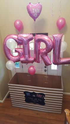 a box filled with pink balloons that spell out the word girl