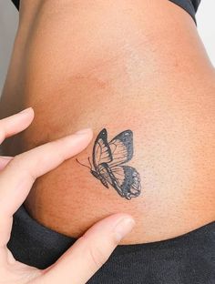 a woman's stomach with a butterfly tattoo on her belly and the bottom part of her lower back