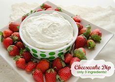 a bowl of cream cheese dip surrounded by strawberries on a white plate with green polka dot trim