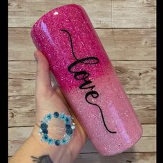 a person holding a pink glitter tumble with the word love on it