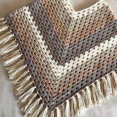 a crocheted blanket with fringes is laying on a bed