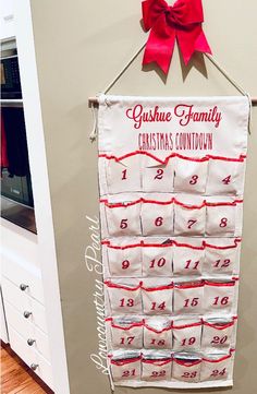 a christmas calendar hanging on the wall in a kitchen with red ribbon around it's edges