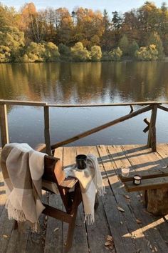 a wooden deck with a table and chair on it next to a body of water