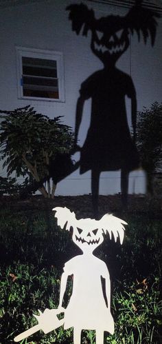 a paper cut out of a person holding a pumpkin in front of a house at night