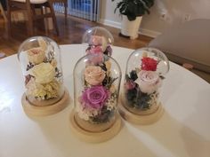 three snow globes with flowers in them on a table