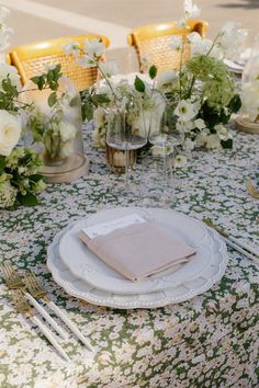 the table is set with white and green flowers, silverware, and napkins