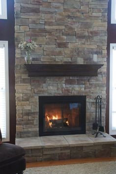 a living room with a stone fireplace and two windows