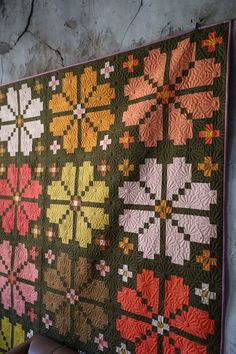 a large quilt hanging on the wall next to a leather chair and table topper