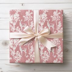 a gift wrapped in pink and white paper with a bow