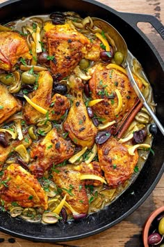 a skillet filled with chicken, olives and onions