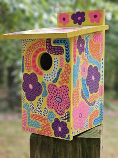 a colorful birdhouse sitting on top of a wooden post