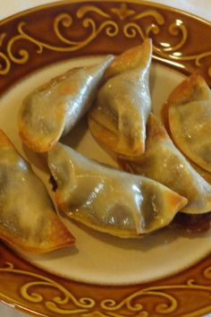 some dumplings are sitting on a brown and white plate