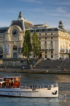 a large white boat floating on top of a river next to a tall brown building